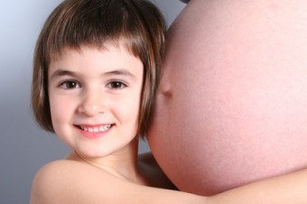 gravidanza - bambina sorridente abbraccia pancia