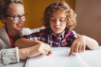 Bimbo ipovedente usa il braille aiutato dall'insegnante di sostegno (Foto d'archivio)